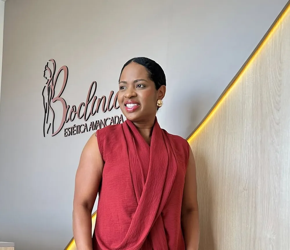 Dra. Fabiana Tavares de macacão vermelho em frente ao logo da Bioclinic
